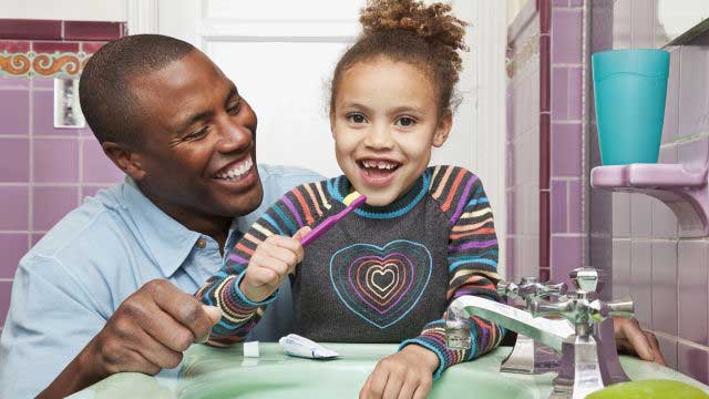 Daughter with her father brushing teeth